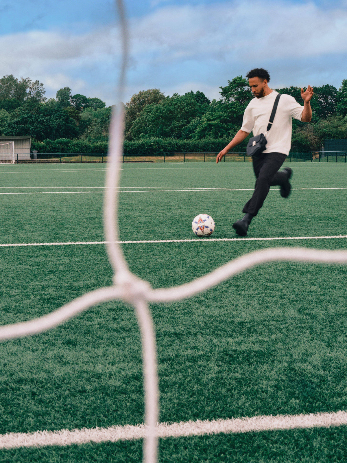 Person playing soccer on a field with trees in the background
