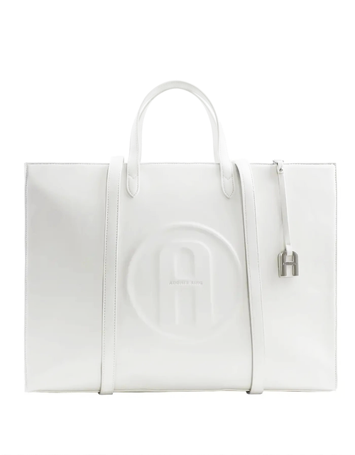 A white leather tote bag with a large embossed circular logo on the front, dual top handles, a side zipper, and a small silver padlock detail, shown against a plain white background.